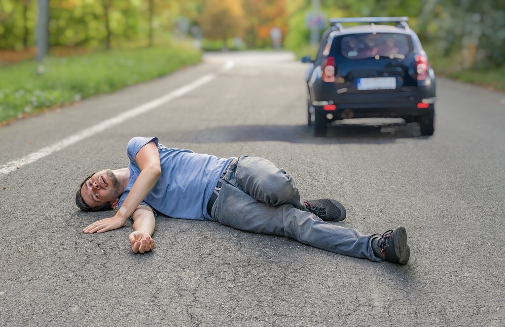 Injured Man On Road In Front Of A Car.